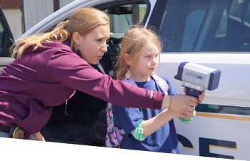 A female officer shows a young girl how to use a radar gun