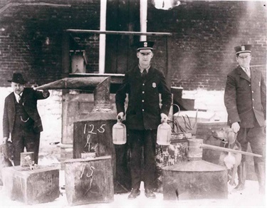 Officer Thomas Boyd (Chief from 1947 - 1967) and Thomas Guthridge are assisted by bloodhounds and Sheriff Luther Pannett at the confiscation of an illegal moonshine still (circa 1920's)